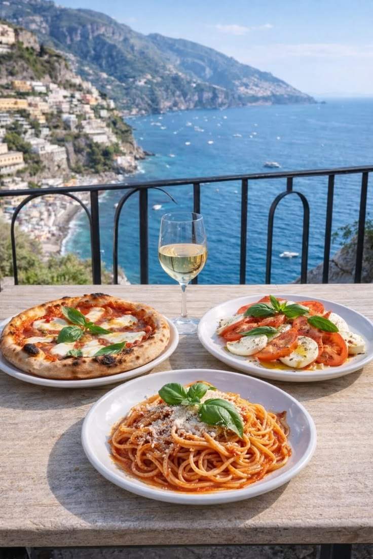 Pizza, caprese e spaghetti al pomodoro con la costa sullo sfondo